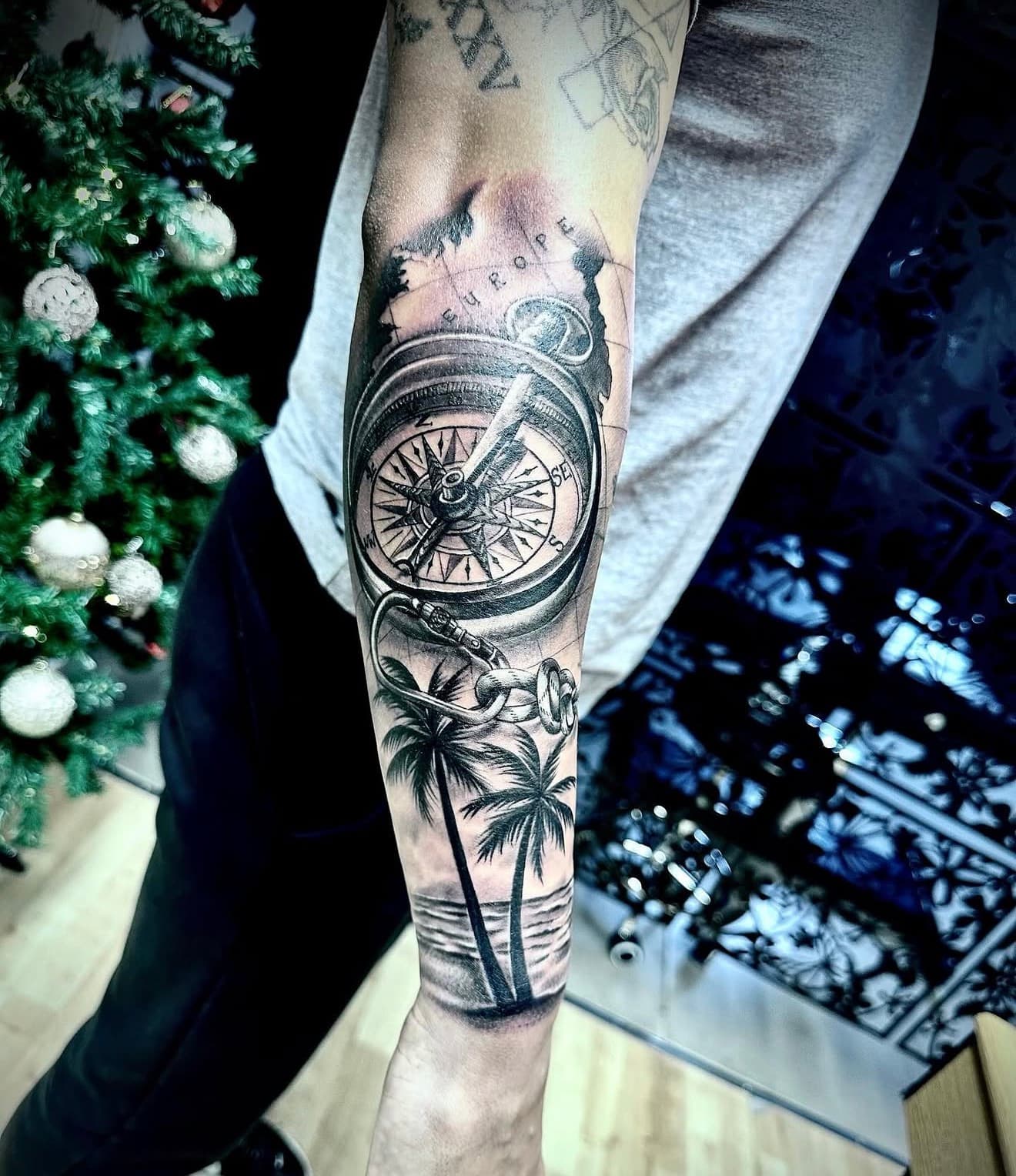 Black and grey compass and palm tree forearm tattoo by Cioffi Tattoo